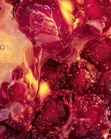 Macro photograph of red and yellow translucent ice cubes with small air bubbles throughout for a refreshing and vibrant abstract.