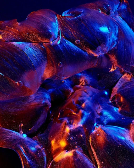 Abstract macro photography of transparent ice crystals illuminated with blue and orange lighting against a dark background.