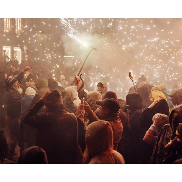 A large crowd in an urban setting during a festival with fireworks, creating a vibrant and festive atmosphere at night.