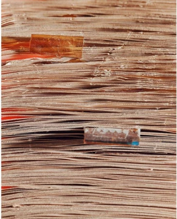 Close-up shot of stacked aged pages, with paper tabs, showcasing texture and detail in muted browns, tans, and a hint of faded red.