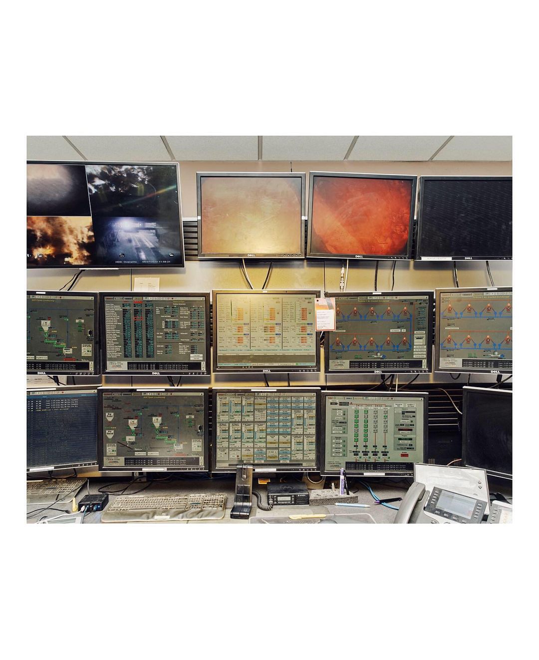 Control room interior with multiple computer screens displaying various data and video feeds, showcasing complex monitoring systems.
