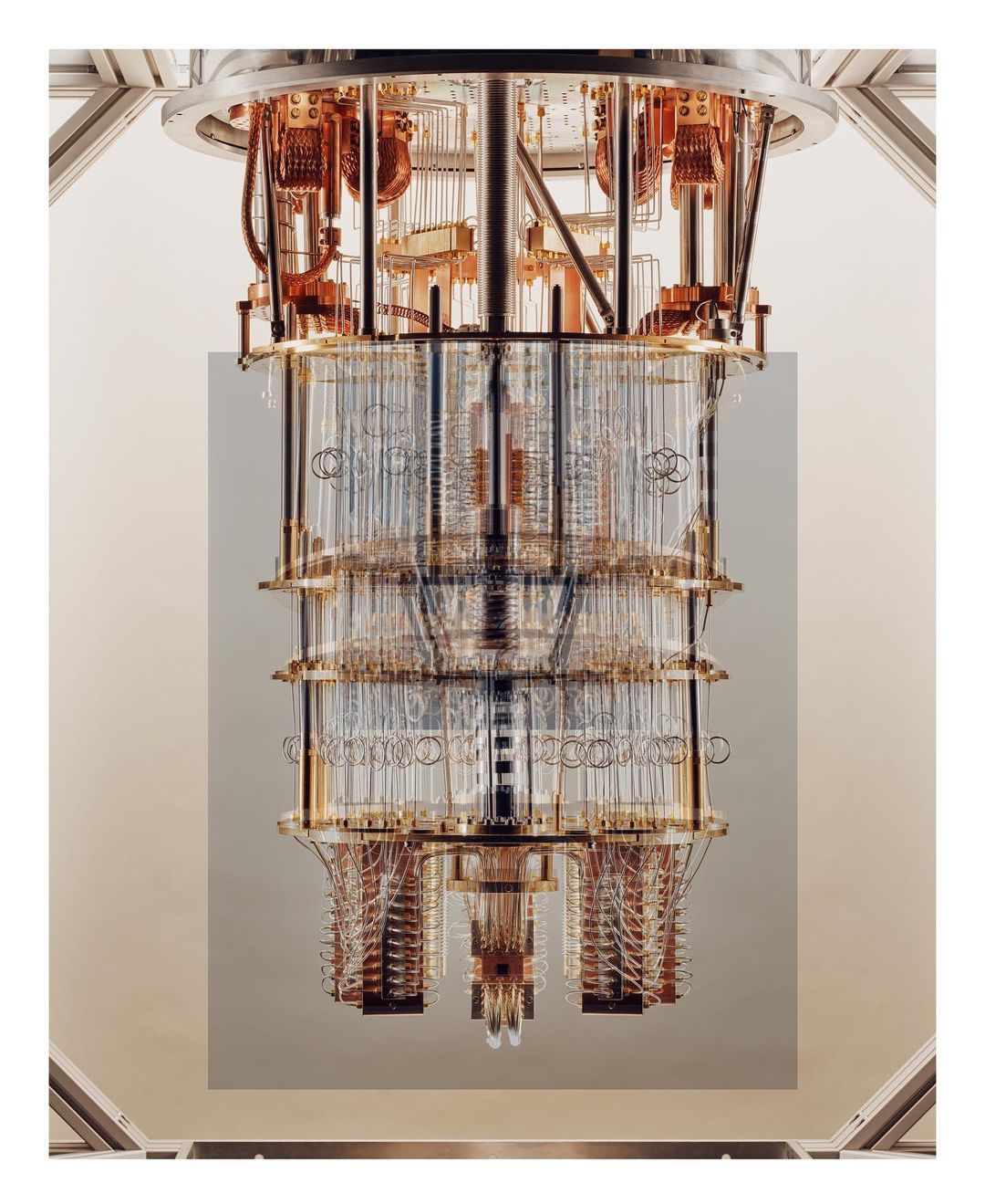 View of a quantum computer with layered cylindrical components, intricate wiring, and a complex design against a neutral backdrop.