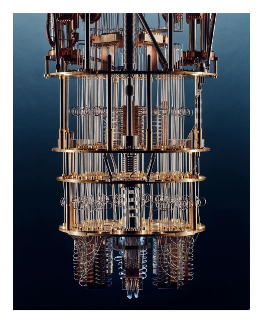 Close-up view of a quantum computing machine with tiered layers of clear tubes, wires, and circular components against a dark blue backdrop.