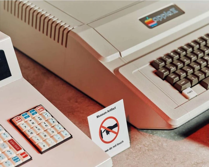 Vintage Apple II computer on display with keyboard and a sign that reads, "Museum Artifact: Please do not touch."