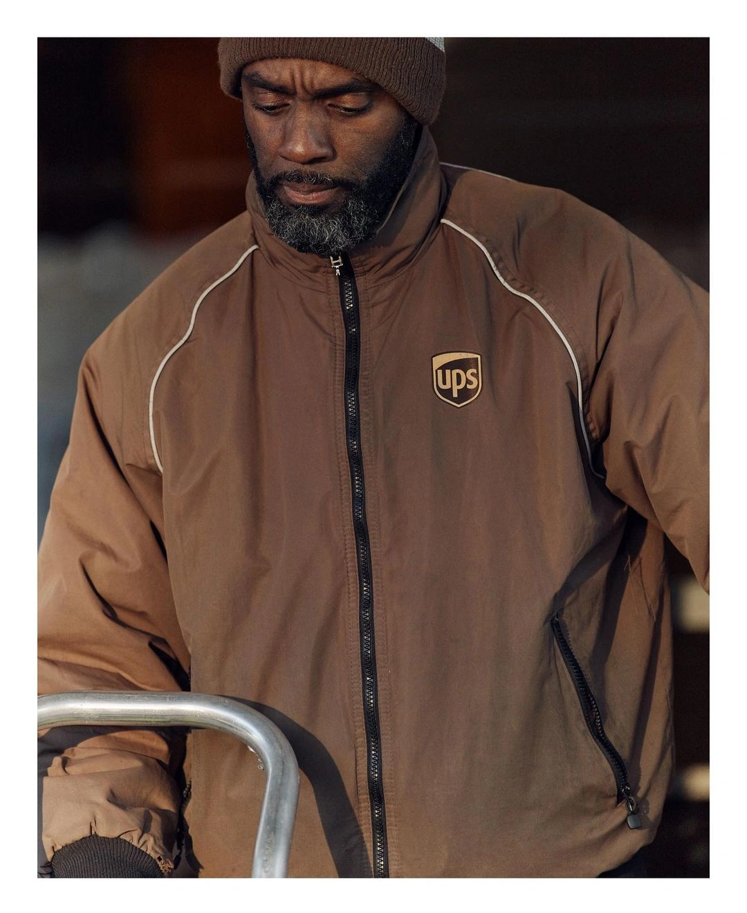 Man wearing a brown jacket with a UPS logo and a beanie in Berlin photographed by Thomas Prior.