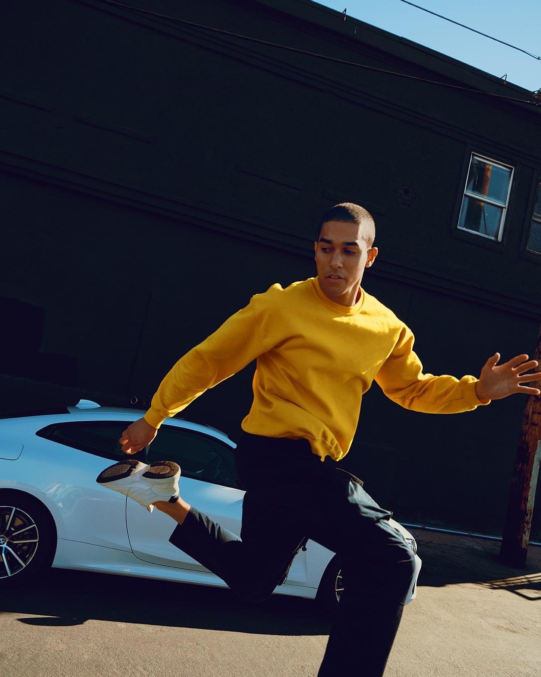 Young man in motion: A stylish individual with a yellow top and dark pants dynamically running in a modern urban setting.