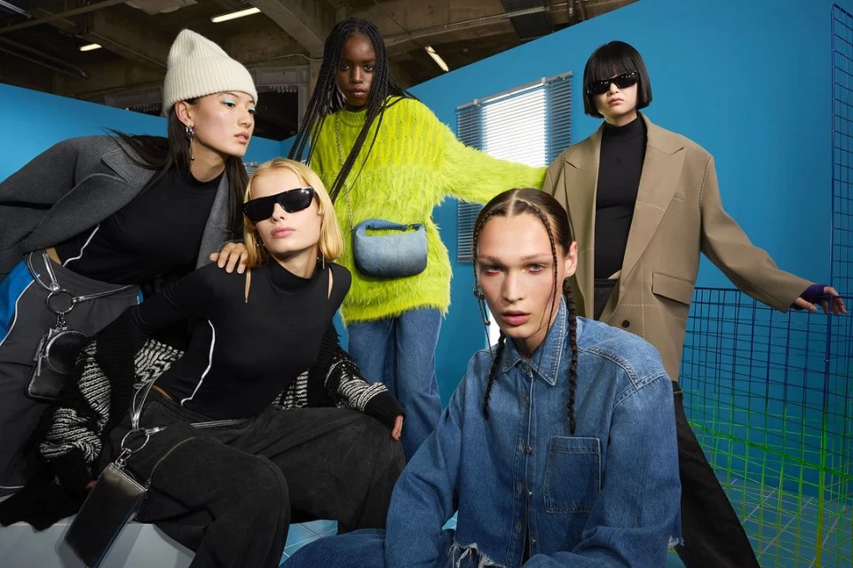 Group of five diverse fashion models in a photo studio wearing fashionable clothing, stylish sunglasses, and holding purses in a studio.