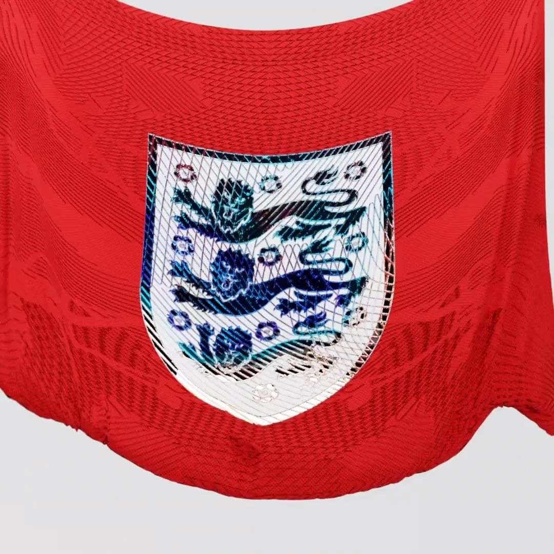Close-up of a red soccer jersey with a shield emblem featuring three lions, set against a plain background.