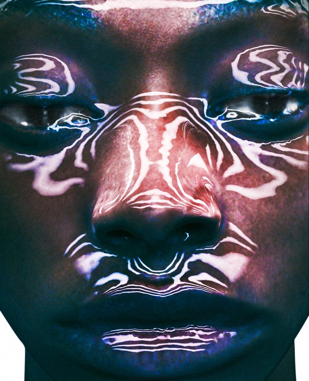 Close-up portrait of a person with white abstract patterns projected on their face in a dark, moody setting with blue and red hues.
