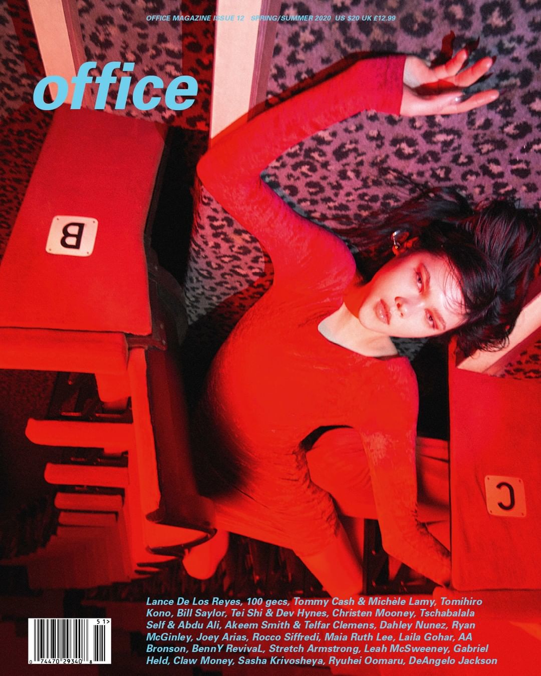 Magazine cover featuring a female model in red dress lying among red geometric objects against a leopard print background. 