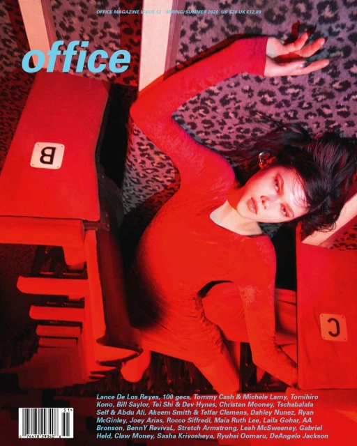 Magazine cover featuring a female model in red dress lying among red geometric objects against a leopard print background. 