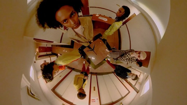 A unique fisheye perspective showing a diverse group of young adults in a stylish indoor setting, showcasing modern fashion and an urban lifestyle.