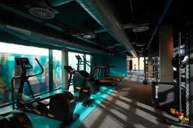 Modern gym interior featuring exercise equipment, treadmills, and exposed ceiling ducts photographed by Tim Evan-Cook.