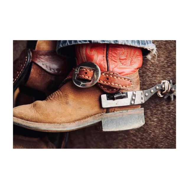 Close-up of leather cowboy boots with metal spurs, stacked heel, and decorative stitching. Rustic western style footwear.