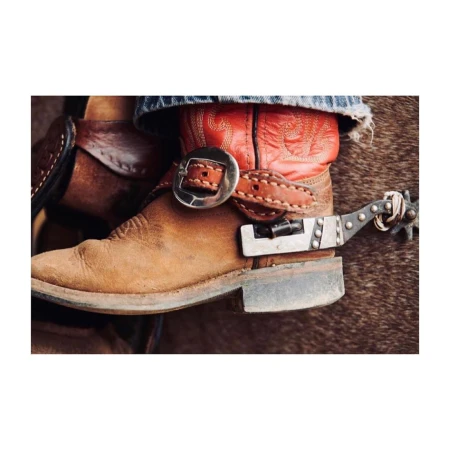 Close-up of leather cowboy boots with metal spurs, stacked heel, and decorative stitching. Rustic western style footwear.