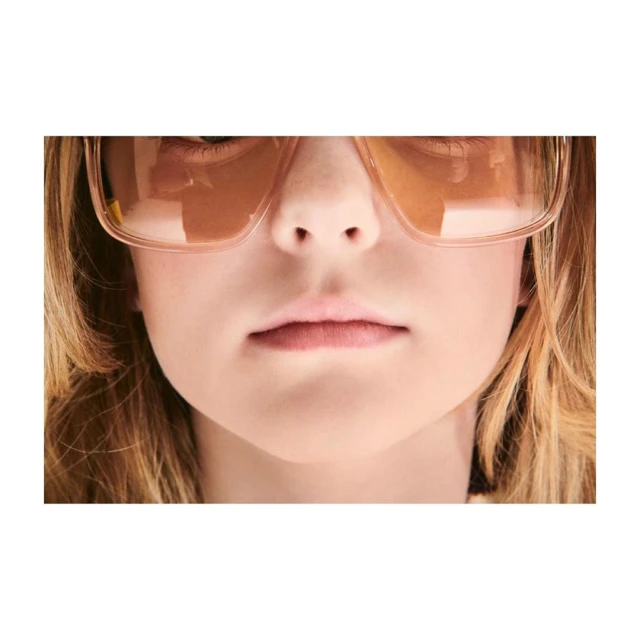 Close-up of a light-skinned child wearing pink-tinted sunglasses, focusing on their eyes, nose, mouth, and facial features.