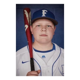 Portrait of young male baseball player wearing a white jersey and blue cap holding a bat by Tim Marsella.