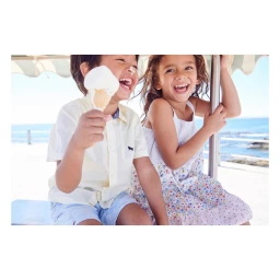 Two children laughing while eating ice cream outdoors near the coast by photographer Tim Marsella