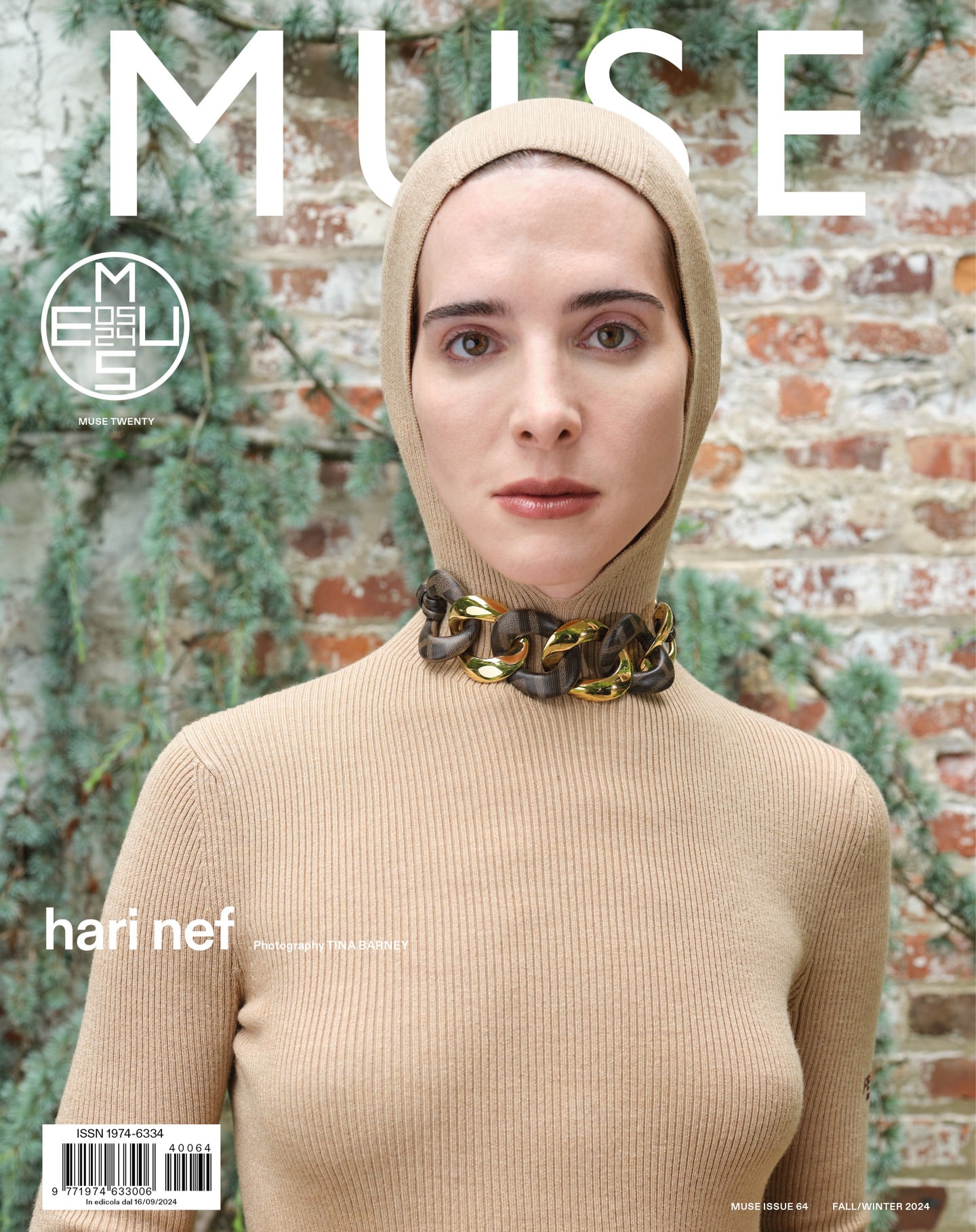 Magazine cover featuring a model wearing a beige hooded turtleneck sweater and statement necklace, set against a lush greenery background.