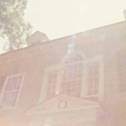 Low angle exterior view of a brick building facade with multi-pane windows under bright sun flare