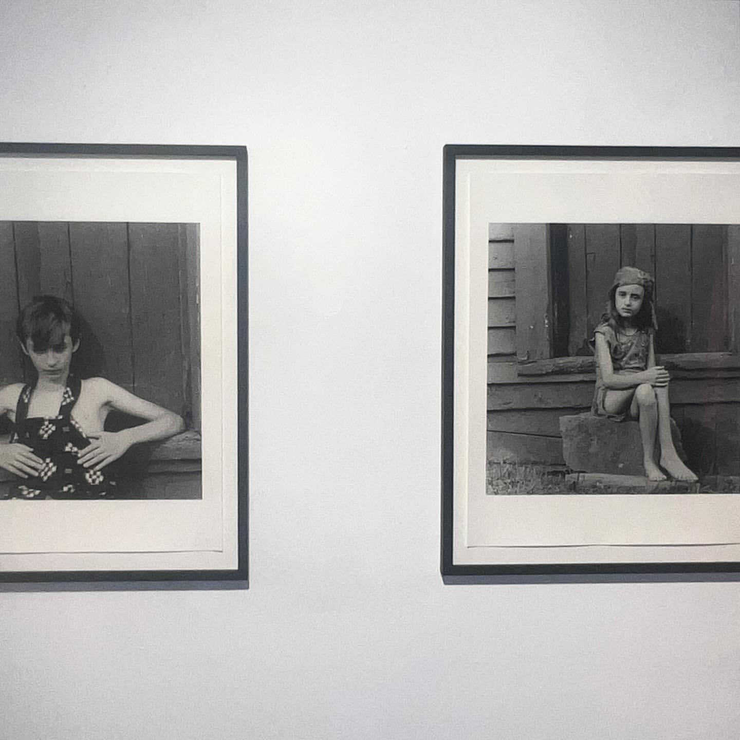Two black and white photographs of children hang side-by-side on a white wall, each framed with a dark frame and a white matte.