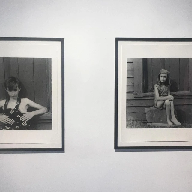 Two black and white photographs of children hang side-by-side on a white wall, each framed with a dark frame and a white matte.