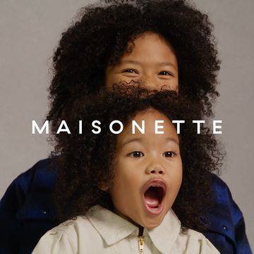 Two children with dark curly hair posing against a neutral grey backdrop, photographed by Tina Tyrell.