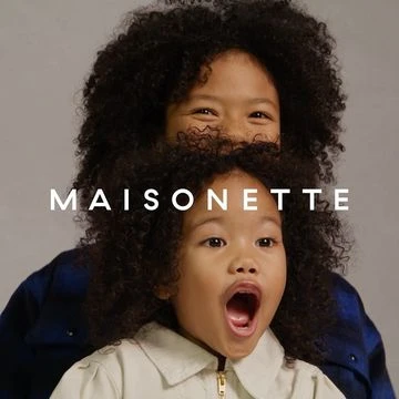 Two children with dark curly hair posing against a neutral grey backdrop, photographed by Tina Tyrell.