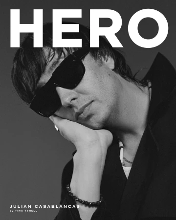 Black and white portrait of Julian Casablancas with sunglasses, resting his chin on his hand, alongside 'Hero' magazine text.