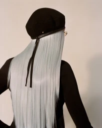 Model with long ice-blue hair wearing a black beret and dark top against a plain white background