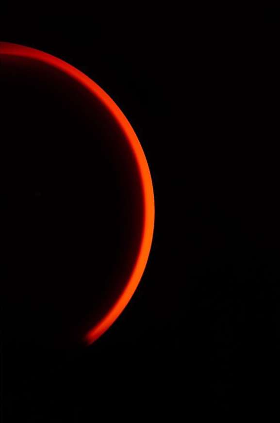 Abstract close-up of a partial red circular shape against a black background, creating a minimalist and striking visual effect.