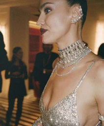 Close-up portrait of a woman wearing a sparkling crystal choker necklace and ear cuff in a dim interior by Tobias Lundkvist.