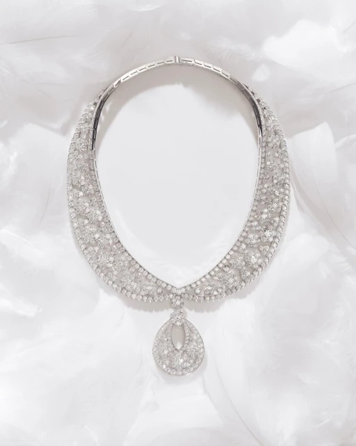 Elegant diamond necklace featuring a teardrop pendant, displayed on a soft white feathered surface, highlighting its intricate design and sparkle.