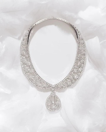 Elegant diamond necklace featuring a teardrop pendant, displayed on a soft white feathered surface, highlighting its intricate design and sparkle.