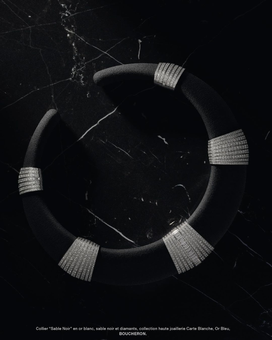Boucheron Sable Noir white gold collar necklace with diamonds displayed on black marble background in a studio shot.