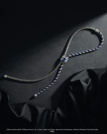 Elegant bolo tie style necklace featuring white gold, sapphires, lapis lazuli, and diamonds, set against a draped black leather surface.