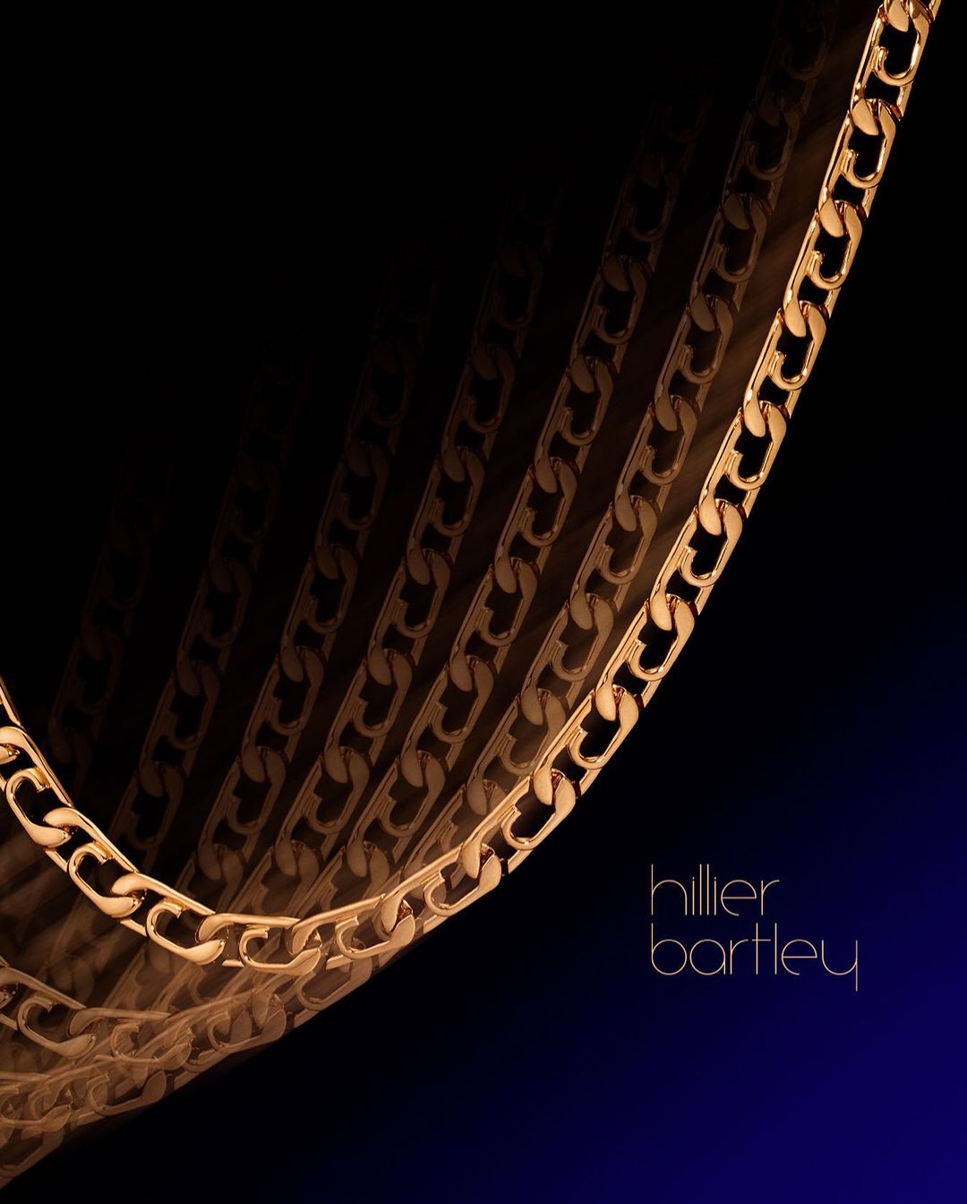 Gold chain necklace against a gradient black-to-blue background with designer Hillier Bartley logo, product photography for fashion.