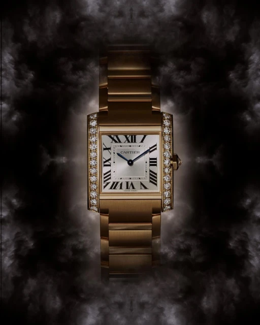 Luxury gold Cartier Tank watch with diamond bezel, set against a dark, smoky background that highlights the watch's details and elegance.