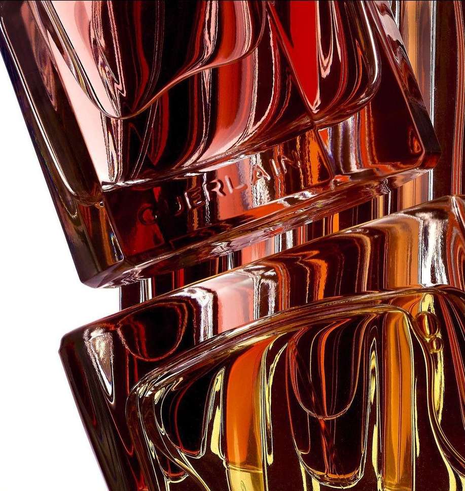 Close-up studio shot of angular, geometric fragrance bottles featuring a metallic finish with reflective surfaces and sharp angles.