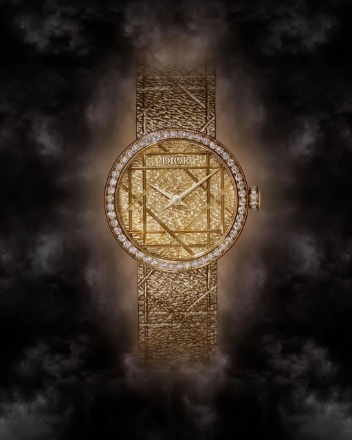 Elegant gold Dior watch with diamond bezel and textured band against a soft black smoky background in a beauty and fashion editorial shot.