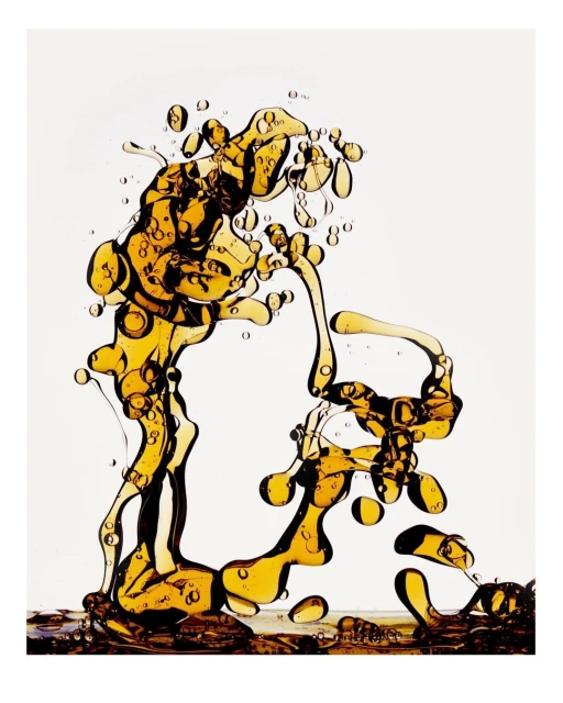 Abstract liquid art featuring transparent golden blobs and thin rivulets against a neutral background, creating a dynamic fluid sculpture.