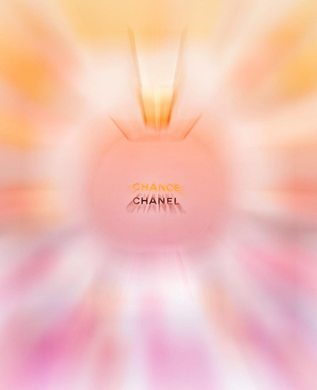 A blurred image showcases a 'Chance Chanel' perfume bottle, its silhouette radiating from a soft-focus blend of pink, orange, and white hues.
