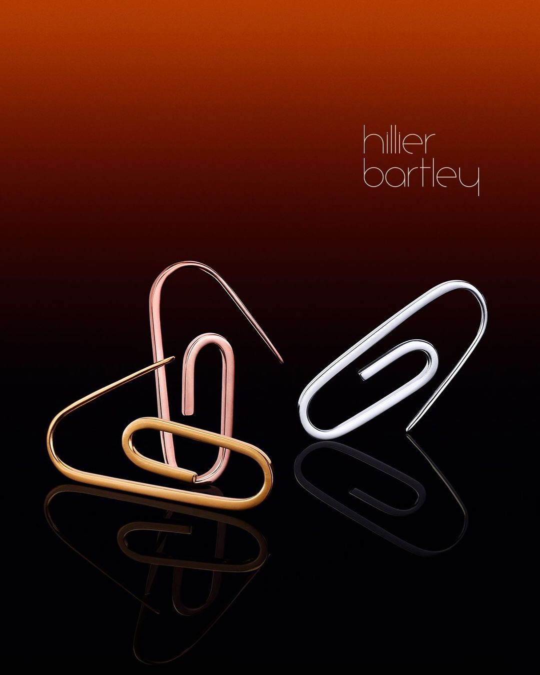 Fashion photography showcasing gold, silver, and rose-gold paper clip earrings against a gradient brown-to-black backdrop with studio lighting.