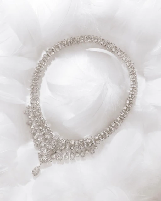 Elegant diamond necklace on a bed of white feathers, showcasing its intricate design and luxurious sparkle against a soft, airy backdrop.