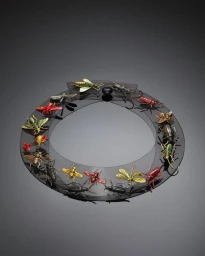An ornate dark translucent circular necklace embellished with metallic insect figurines photographed by Toby Mcfarlan Pond.