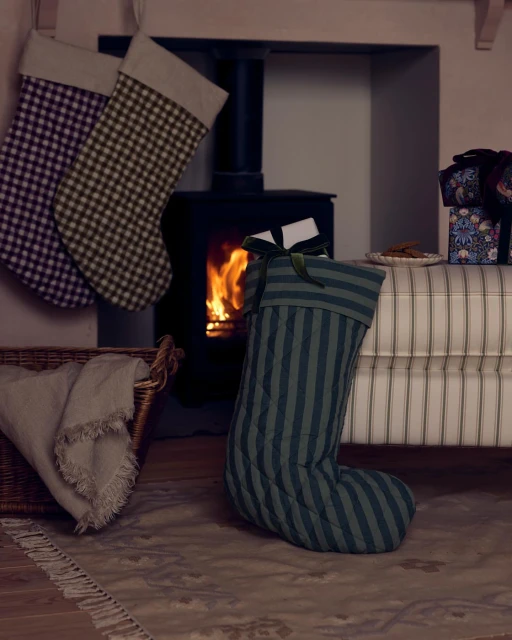 Holiday scene features Christmas stockings hanging near a fireplace with presents, a festive and cozy interior arrangement.