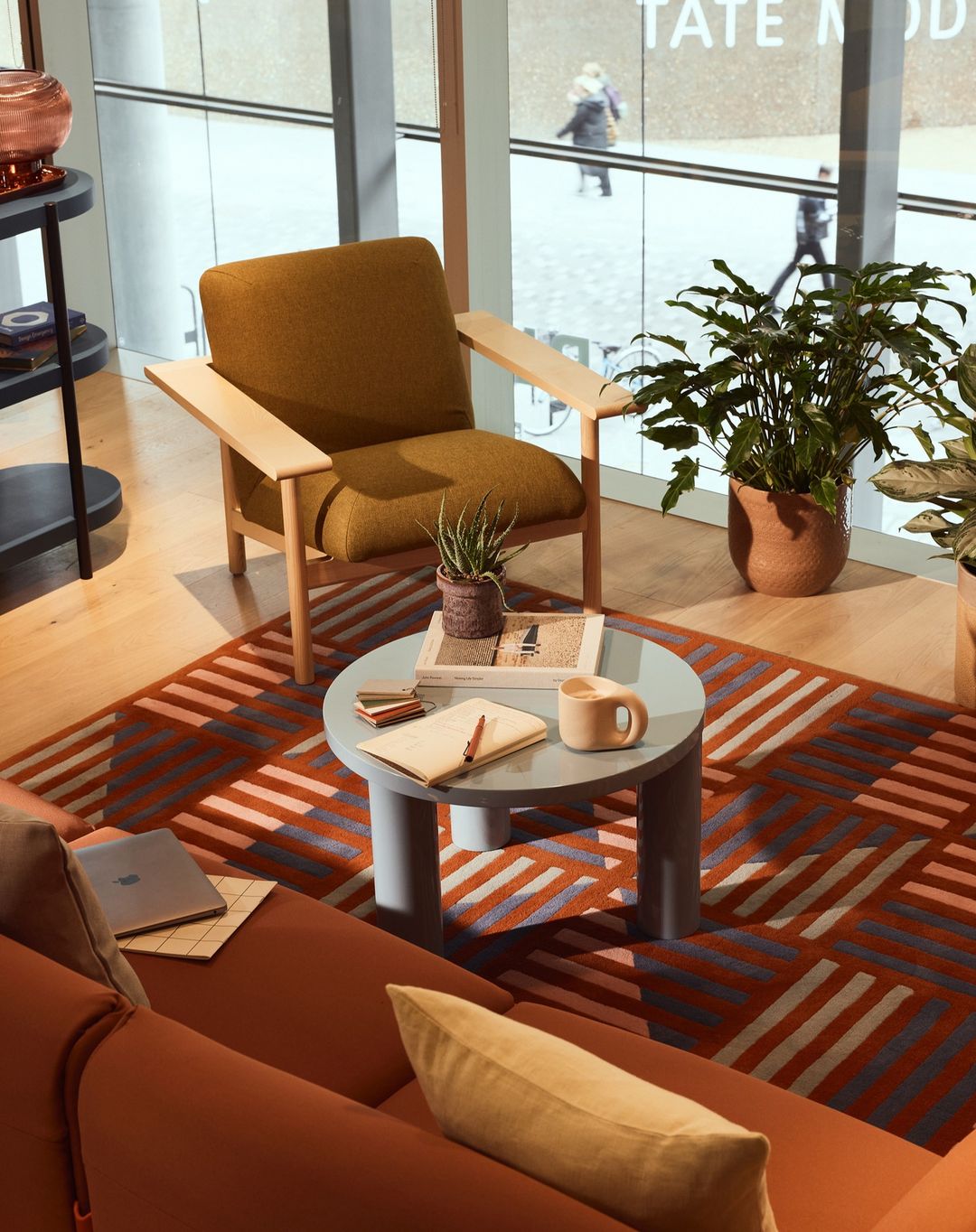 Interior shot featuring a mustard-colored chair, a round coffee table with decor, and a rust-colored couch in a modern space.