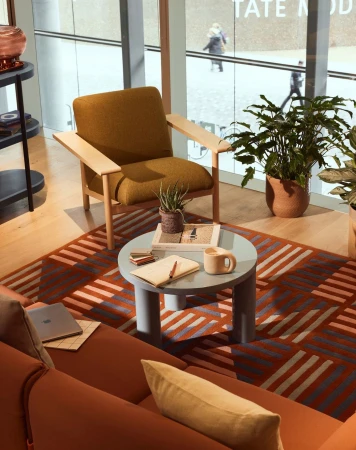 Interior shot featuring a mustard-colored chair, a round coffee table with decor, and a rust-colored couch in a modern space.
