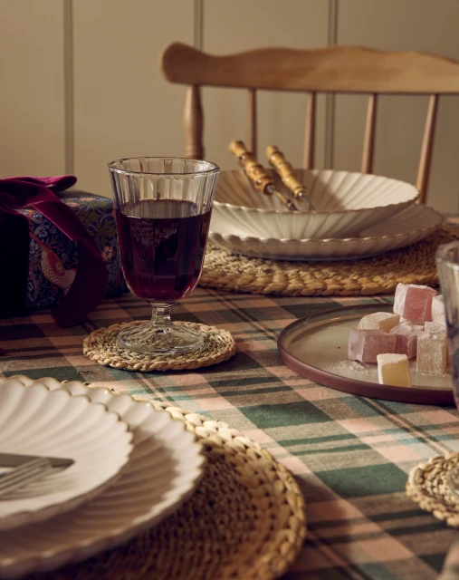 Still-life shot of a table setting with a wine glass, plates, Turkish delight, and a gift box under warm studio lighting.