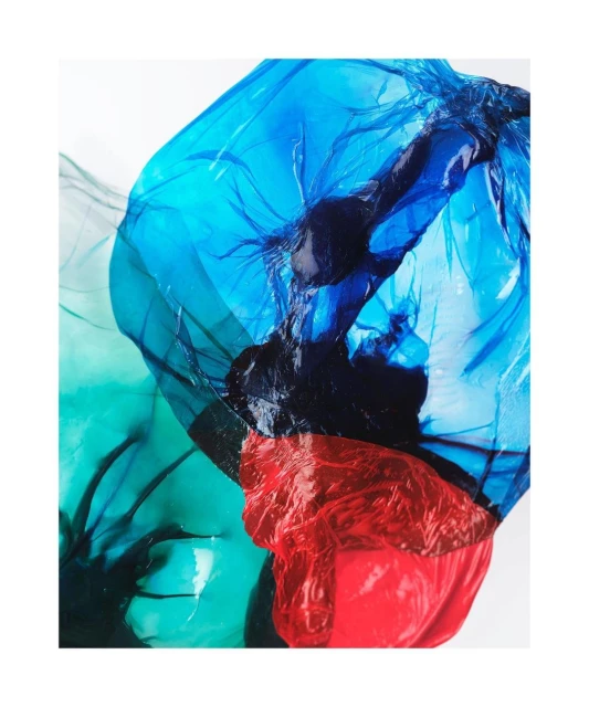 Abstract image featuring translucent overlapping plastic sheets in vibrant blue, red, and green colors against a bright white background.